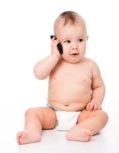 Cute little baby is talking on cell phone, isolated over white